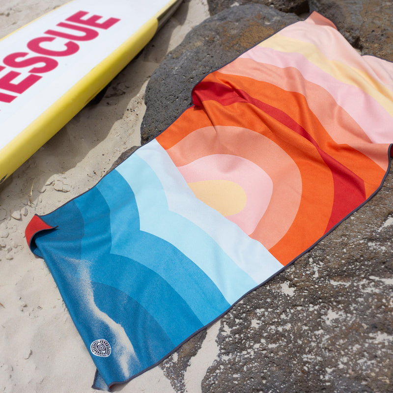 The Summer Chaser travel towel in Dipping Sun design in action on the beach.